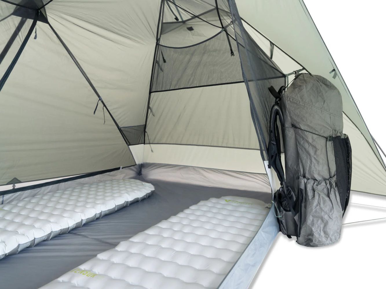 Two sleeping pads and a backpack arranged inside a two-person backpacking tent