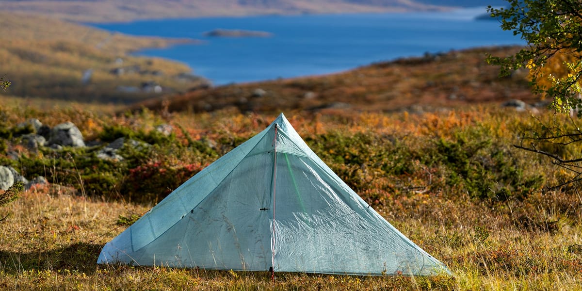 Backpacking tent set up beside a pack on a trail campsite